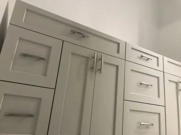 A white cabinet with many drawers and pulls.